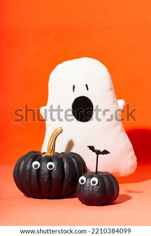 Two black pumpkins with eyes and ghoast on an orange background. Pumpkin monsters, funny Halloween vertical card