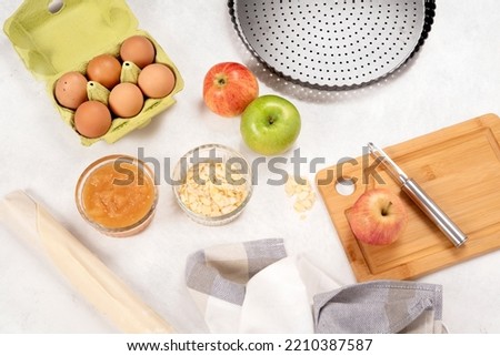 Apple pie. Recipe. Raw ingredients. Ready to cook. Preparation. Healthy cooking. Homemade. Apples, puff pastry, eggs, compote, almonds. Family cooking. Recipe concept, preparation. Utensil.
