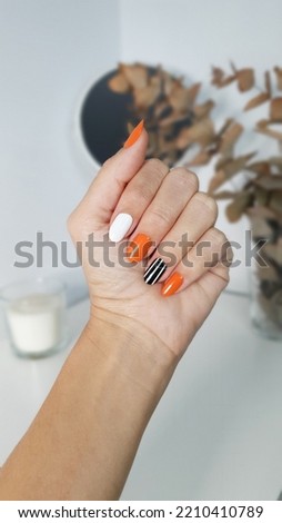 Nail art in white, orange and black stripes for fall or halloween Royalty-Free Stock Photo #2210410789