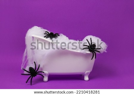 Halloween bathtub filled with black spiders on purple background. Halloween background. Scary concept. Podium for products