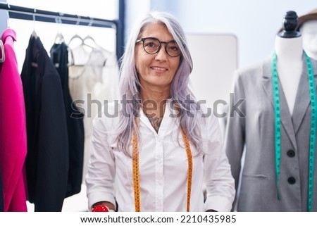 Middle age grey-haired woman tailor smiling confident standing at tailor shop