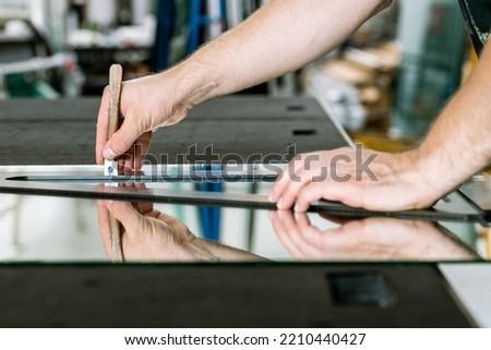 Glazier cuts a mirror on a special table, Glass industry Royalty-Free Stock Photo #2210440427