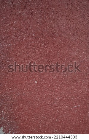Old weathered concrete wall painted in red with stains and uneven surface