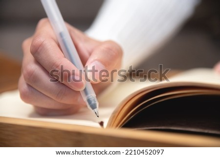 close-up, female hands hold a pen and write in a notebook the daily schedule, an office worker or a freelancer