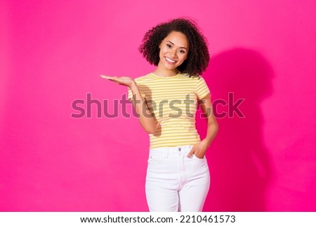 Photo portrait of pretty young girl palm holding empty space dressed stylish yellow striped outfit isolated on bright pink color background