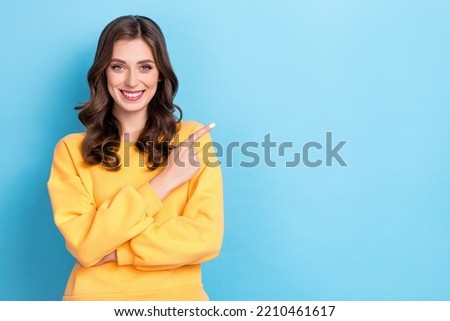 Closeup photo of young pretty nice gorgeous girl wear yellow pullover finger point empty space recommend product ad isolated on blue color background