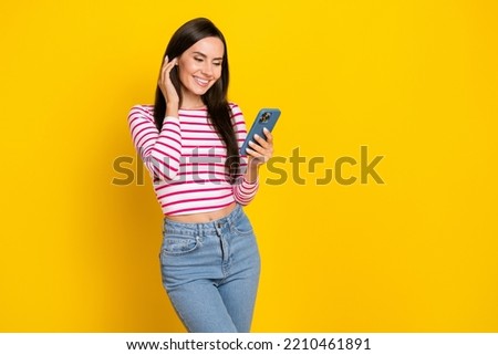 Portrait photo of young girlish cute lady touch hair smiling user webcam model phone isolated on yellow color background
