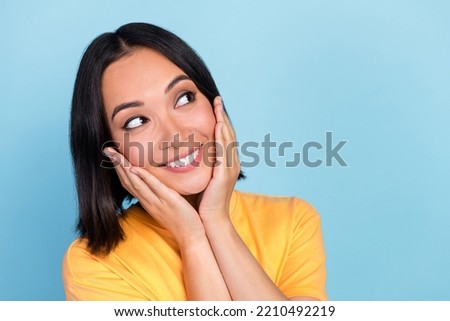 Portrait of gorgeous girl with bob hairstyle wear yellow t-shirt palms on cheekbones look empty space isolated on blue color background