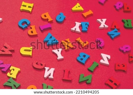 Random colorful alphabet on a red background, colorful letters. Top view.