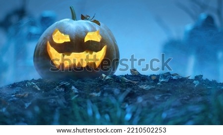 Glowing Halloween pumpkin among the graves in the cemetery. Holiday event halloween concept.