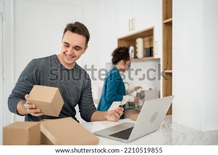 Young caucasian couple woman and man wife and husband or girlfriend and boyfriend opening gifts box presents and read card in front of laptop computer at home having online video call happy copy space