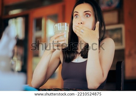 
Woman Reacting after Drinking a Sour Beverage. Unhappy girl drinking a citrus beverage with a bad taste
 Royalty-Free Stock Photo #2210524875