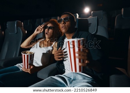 A couple in love, friends watching a movie with popcorn in the cinema. High quality photo