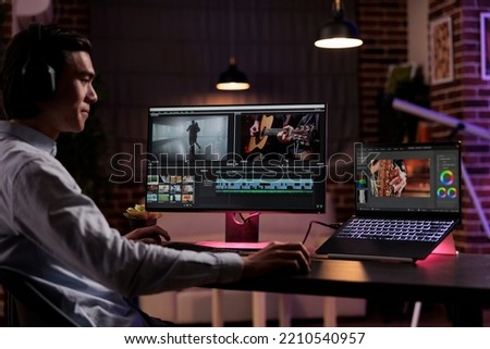 Asian editor working on movie production with computer software, editing film montage with audio and visual effects. Creating multimedia content with footage, color grading creative app.