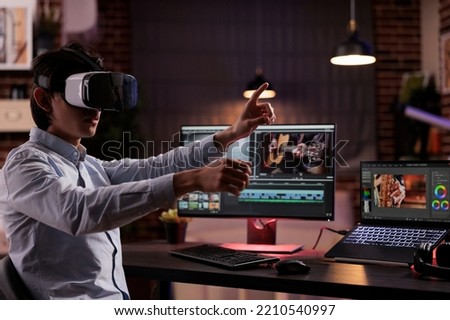 Freelancer using vr glasses to edit movie footage with computer software app. Videographer editing film montage with visual and sound effects, creating video for multimedia production. Royalty-Free Stock Photo #2210540997