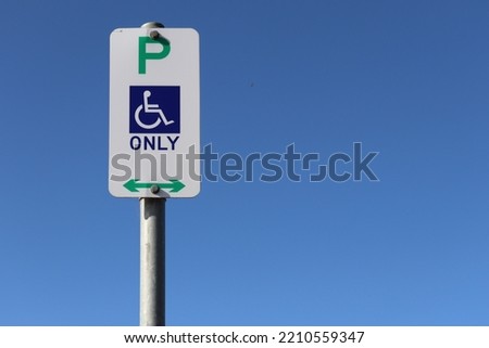 wheelchair car parking sign in car park against blue sky
