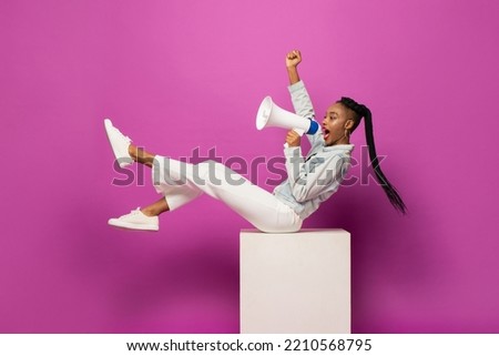 Young African American woman shouting on megaphone and raising fist in studio purple pink color isolated background Royalty-Free Stock Photo #2210568795
