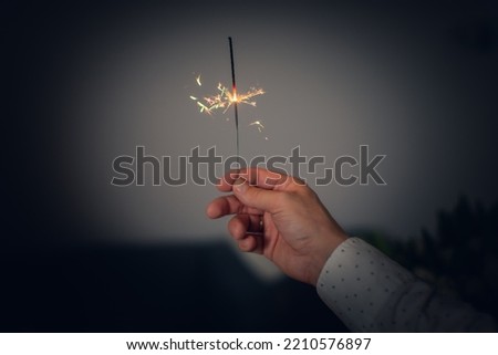 A man's hand holds a burning sparkler fire on a white background. Front view. Royalty-Free Stock Photo #2210576897