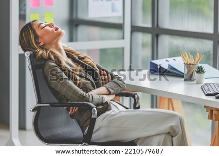 Millennial Asian tired exhausted female businesswoman employee in formal business suit sitting crossed arms close eyes sleeping napping take break on chair at workstation desk in company office.