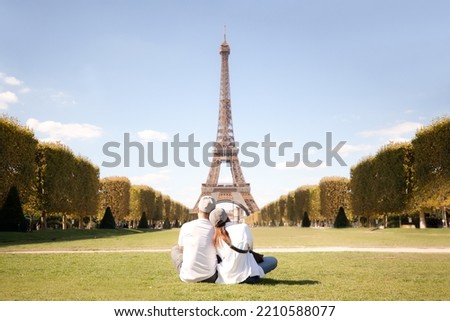 Couple sitting on grass looking at the Eiffel Tower Royalty-Free Stock Photo #2210588077