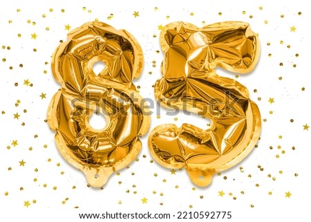 The number of the balloon made of golden foil, the number eighty five on a white background with sequins. Birthday greeting card with inscription 85. Anniversary concept. Royalty-Free Stock Photo #2210592775