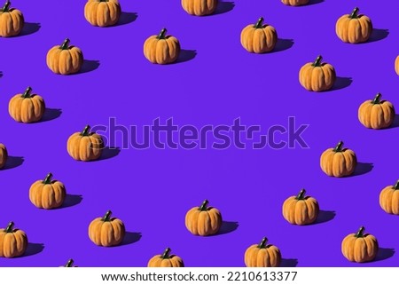 Decorative pumpkins, creative pattern with central copy space, on purple background. Halloween celebration idea. 