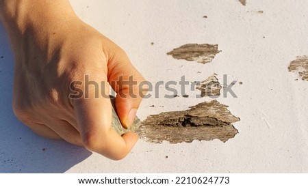 Someone scraping wooden table with stone.