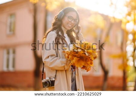 Young woman taking pictures in the autumn forest. Lady Walking In Fall Park With Yellow Foliage.