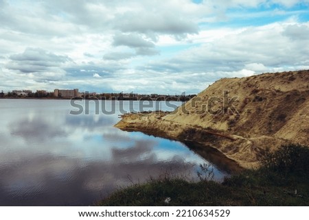 cloudy sky over the lake, sandy shore, autumn trees, landscape in Ukraine Kharkiv. Beautiful natural background.