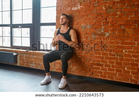 Athlete doing training exercise against gym wall Royalty-Free Stock Photo #2210643573