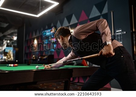 Young man playing billiard at night club Royalty-Free Stock Photo #2210643593