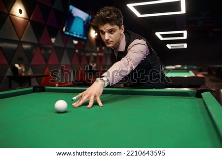 Portrait of young man aiming with billiards cue Royalty-Free Stock Photo #2210643595