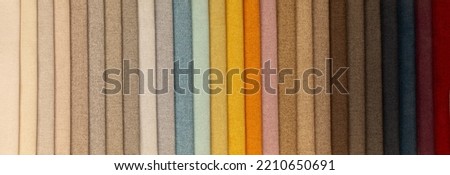Fabric texture close up. Fabric swatches in different colors are stacked for selection. A variety of shades of upholstery material for furniture and interior. A set of multi-colored rolls of material. Royalty-Free Stock Photo #2210650691