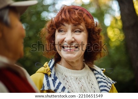 Happy senior couple women looking at each other walking in the forest holding hands. Caucasian active elderly gray haired people enjoying vacation freedom and nature hiking in footpath in a sunny day