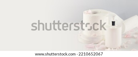 Hygiene banner with roll of toilet paper with cosmetic dispenser bottle on light background with copy space. White toilet tissue. Restroom soft touch toilet paper. Soft focus style, banner size Royalty-Free Stock Photo #2210652067