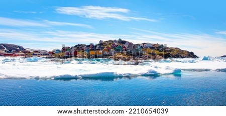 Panoramic view of colorful Kulusuk village in East Greenland - Kulusuk, Greenland - Melting of a iceberg and pouring water into the sea - Drummer statue in the foreground