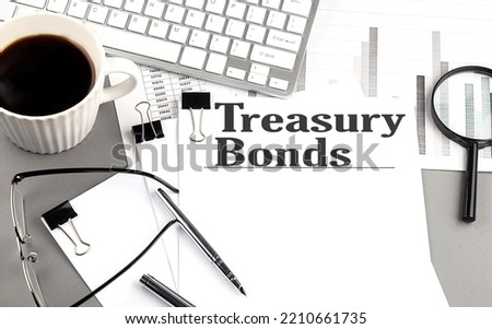 TREASURY BONDS text on paper with magnifier, coffee and keyboard on grey background