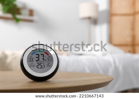 Digital hygrometer with thermometer on wooden table indoors. Space for text Royalty-Free Stock Photo #2210667143
