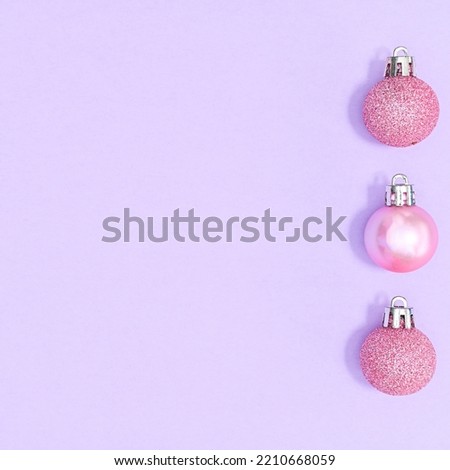 Pastel pink Christmas ornaments on pastel purple background with copy space. FLat lay
