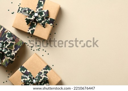 Gift boxes with camouflage military ribbon bow and confetti on beige background. USA Veterans Day holiday concept.