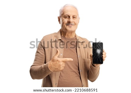 Casual mature man holding a smartphone and pointing at the broken screen glass isolated on white background