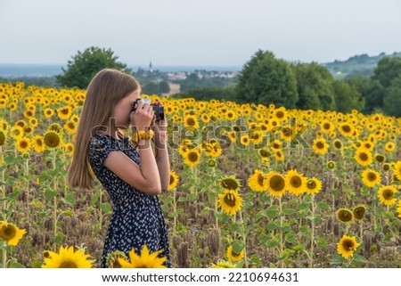 Girl taking a picture in a field of sunflowers