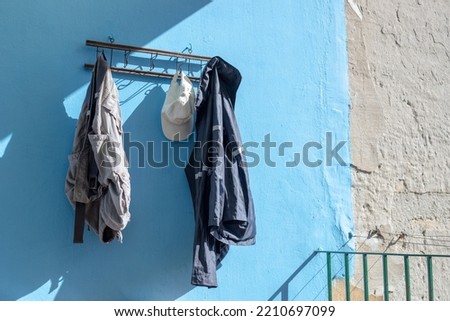 Short pants, white cap and jacket hanging on a blue wall.