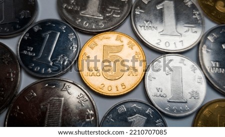 Lots of Chinese coins, in the center is a five-jiao coin. A 5 jiao coin is shot in close-up. In the background, several coins of one yuan, one and five jiao