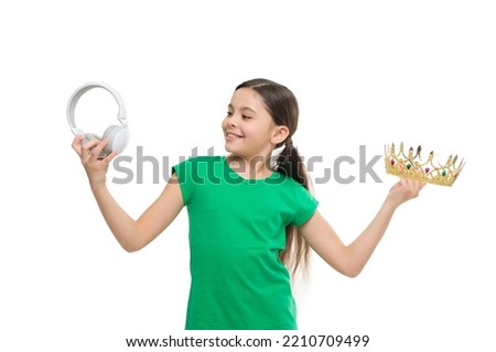 small girl choose between crown and headphones. being a super star. best hit list. royalty free music. pop princess. queen of music. portrait of cheerful girl isolated on white. happy childhood
