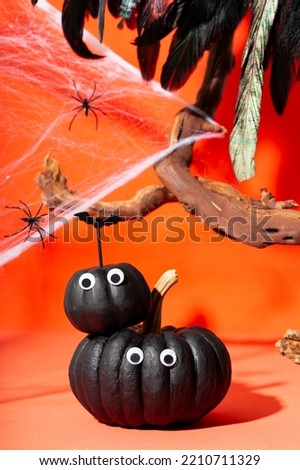 Two black pumpkins with eyes and web spiders on an orange background. Pumpkin monsters, funny Halloween vertical card