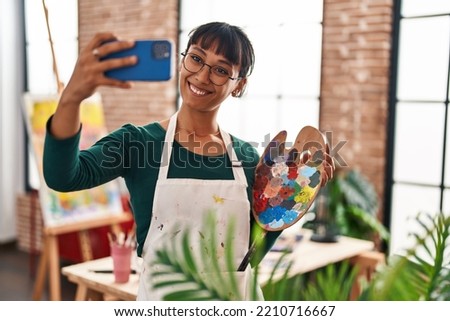 Young beautiful hispanic woman artist smiling confident make selfie by smartphone at art studio
