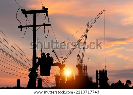 Silhouette of Electrician officer climbs a pole and uses a cable car to maintain a high voltage line system, Shadow of Electrician lineman repairman worker at climbing work on electric post power pole Royalty-Free Stock Photo #2210717743