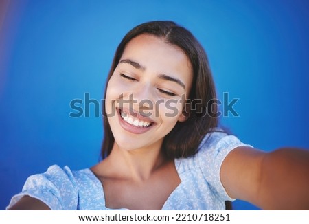 Happy woman with natural beauty, selfie for social media and with a smile on her face on blue background. Portrait of a pretty young girl, wellness and photo of glowing healthy skin on summer holiday