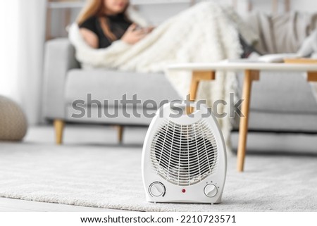 Electric fan heater on carpet in living room Royalty-Free Stock Photo #2210723571